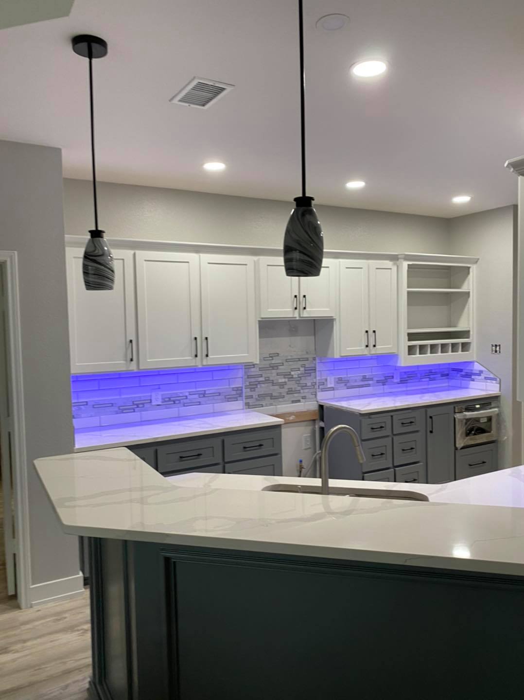 Kitchen remodel with white and gray cabinets, marble counters, and LED under-cabinet lighting