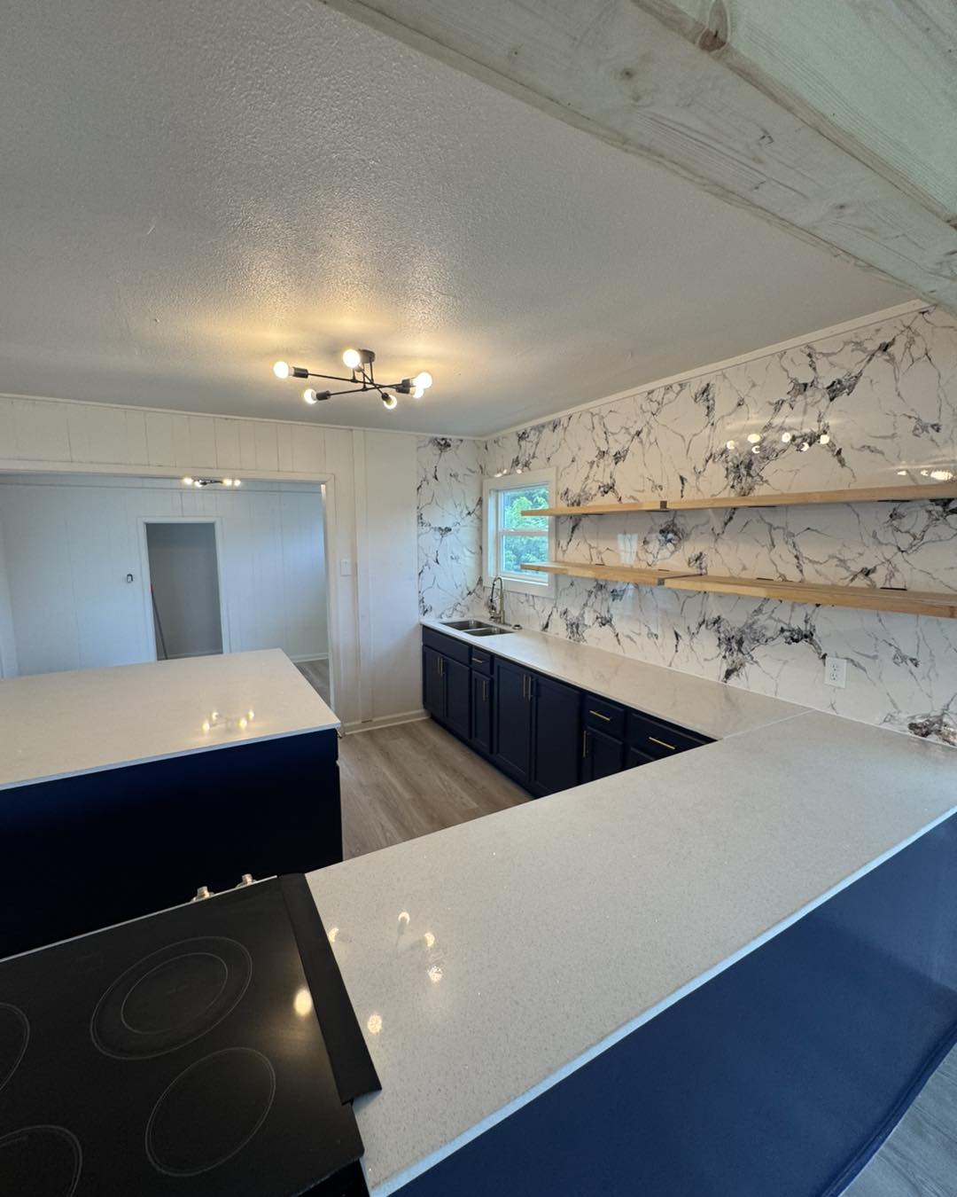 Navy blue kitchen cabinets with marble slab backsplash and open shelving