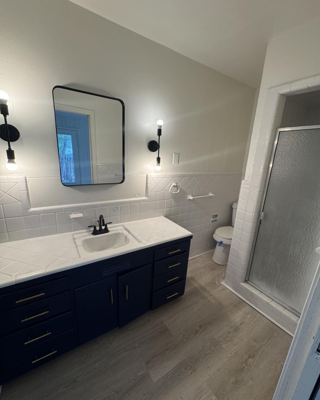Bathroom with navy double vanity, white tile surround, and matte black fixtures