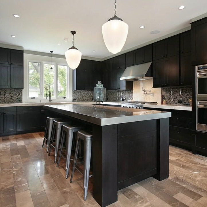 Kitchen with dark cabinets, large island with bar seating, and pendant lights
