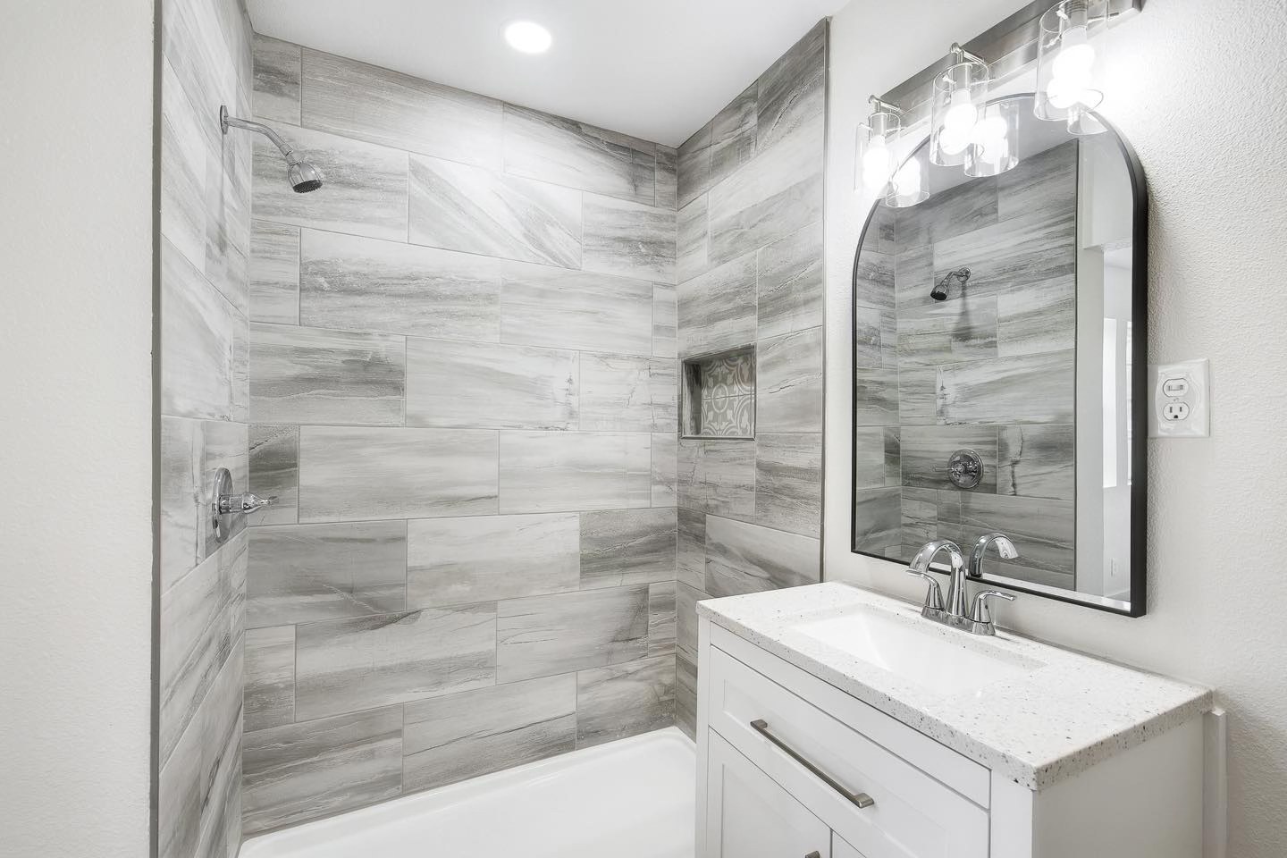 Bathroom with large-format gray marble-look tile shower and white quartz vanity