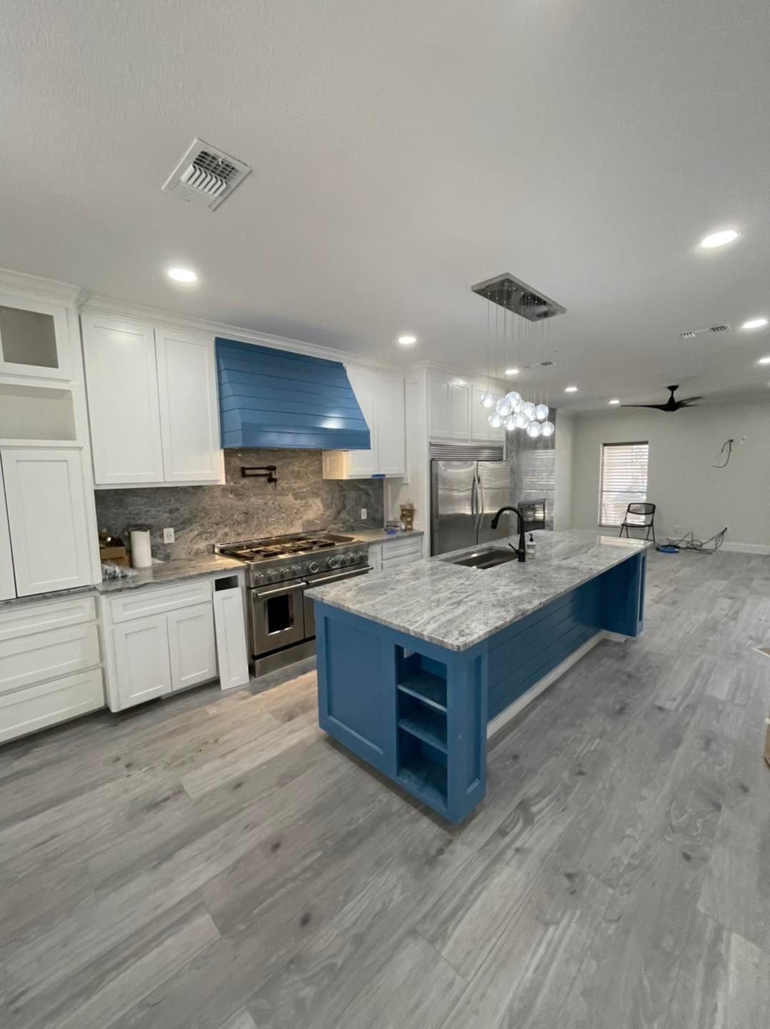 Custom kitchen remodel with blue island, marble counters, white cabinets, and blue range hood