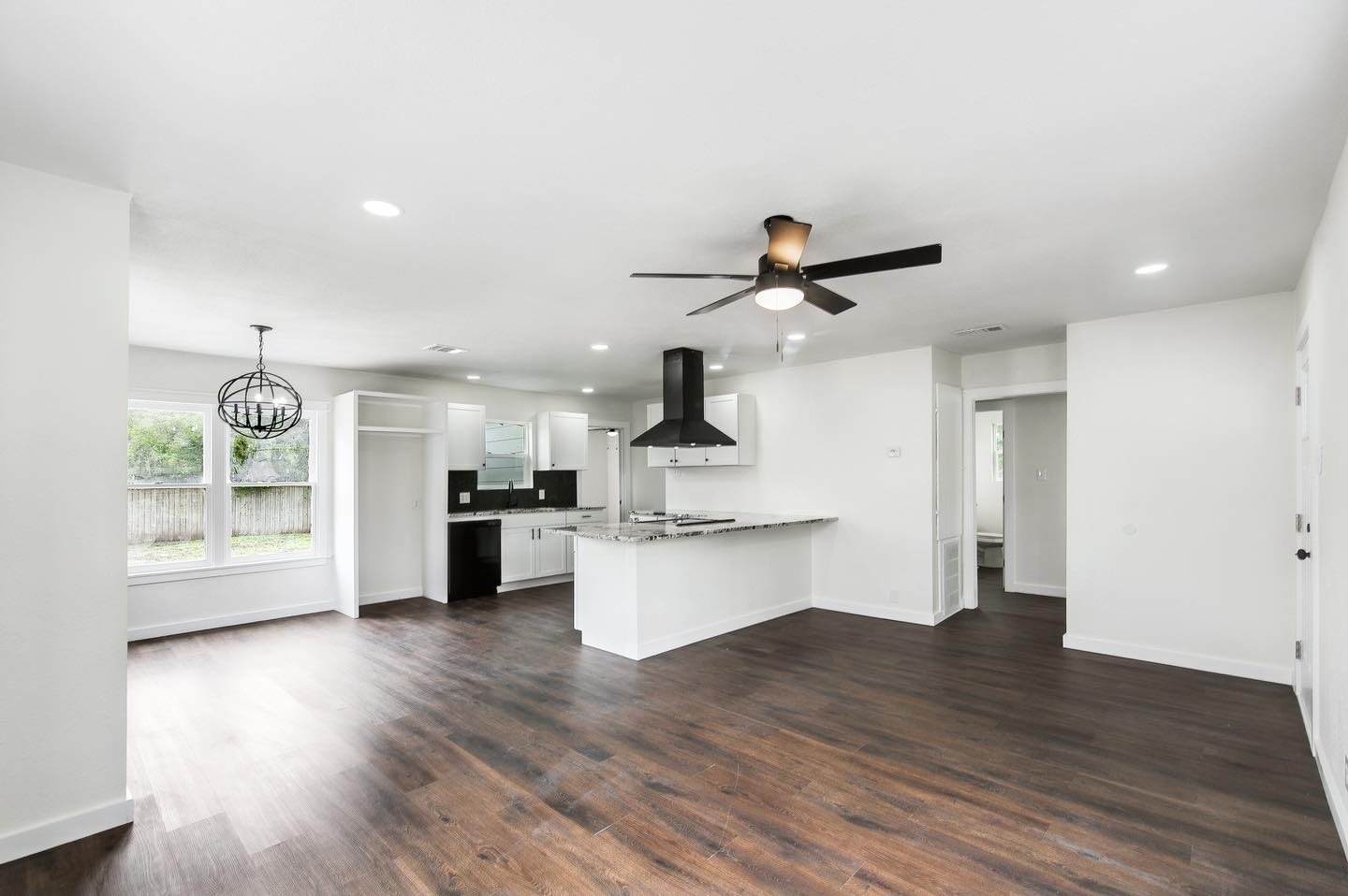 Open living and kitchen remodel with dark floors, white walls, and recessed lighting