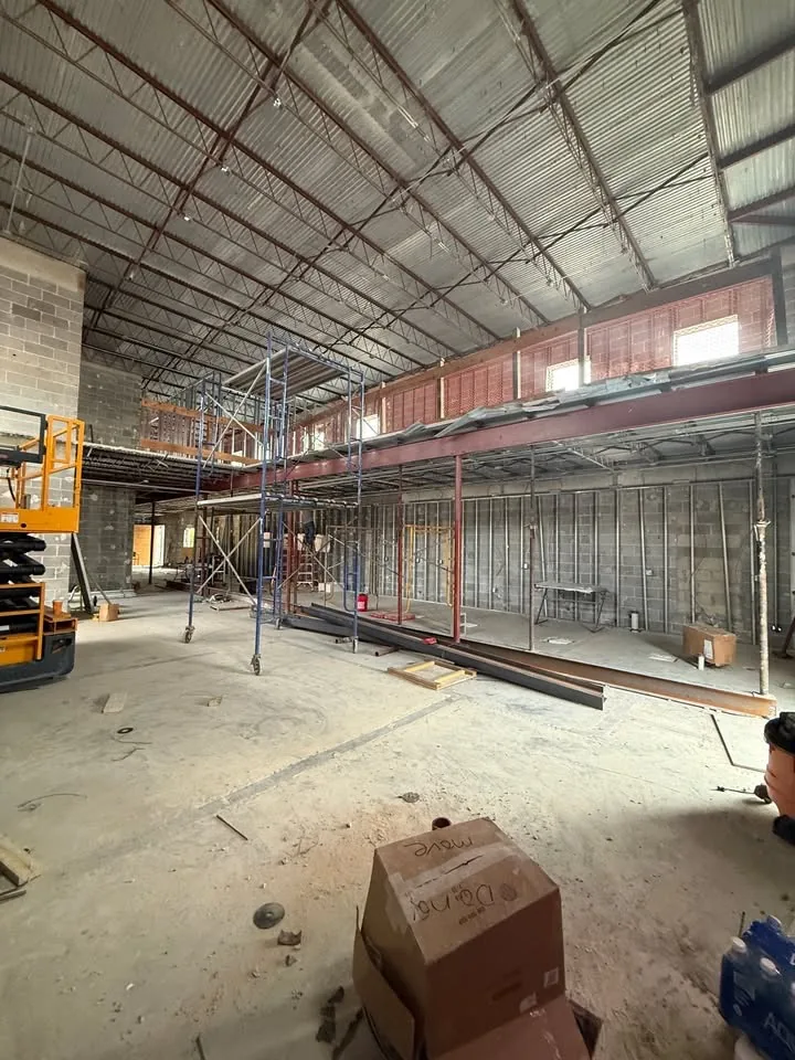 Gutted commercial shell before renovation, exposed steel joists and CMU walls