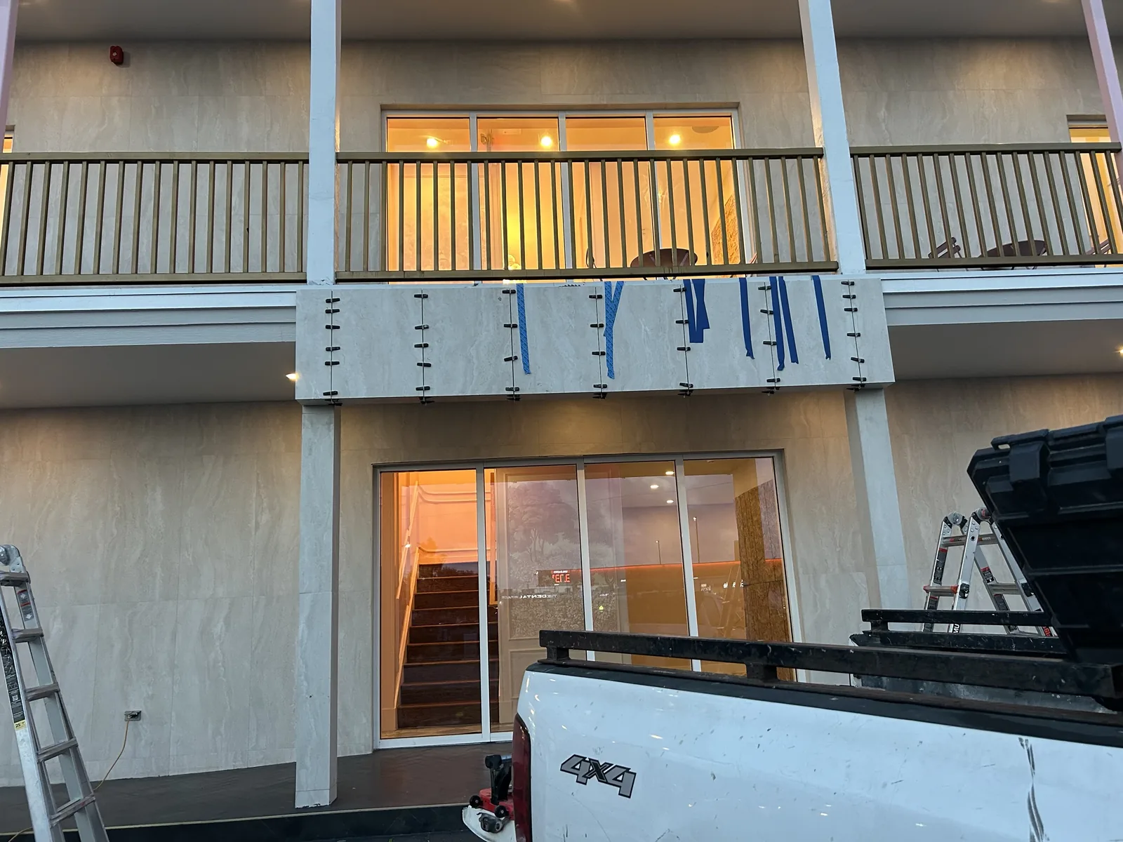 Two-story exterior with balcony railing and stone cladding under construction