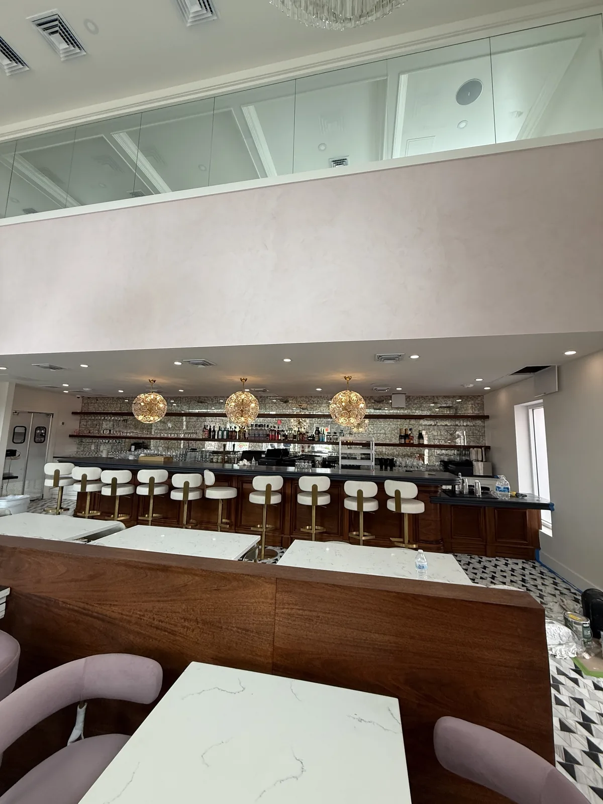 Bar elevation with Venetian plaster mezzanine wall and glass guardrail
