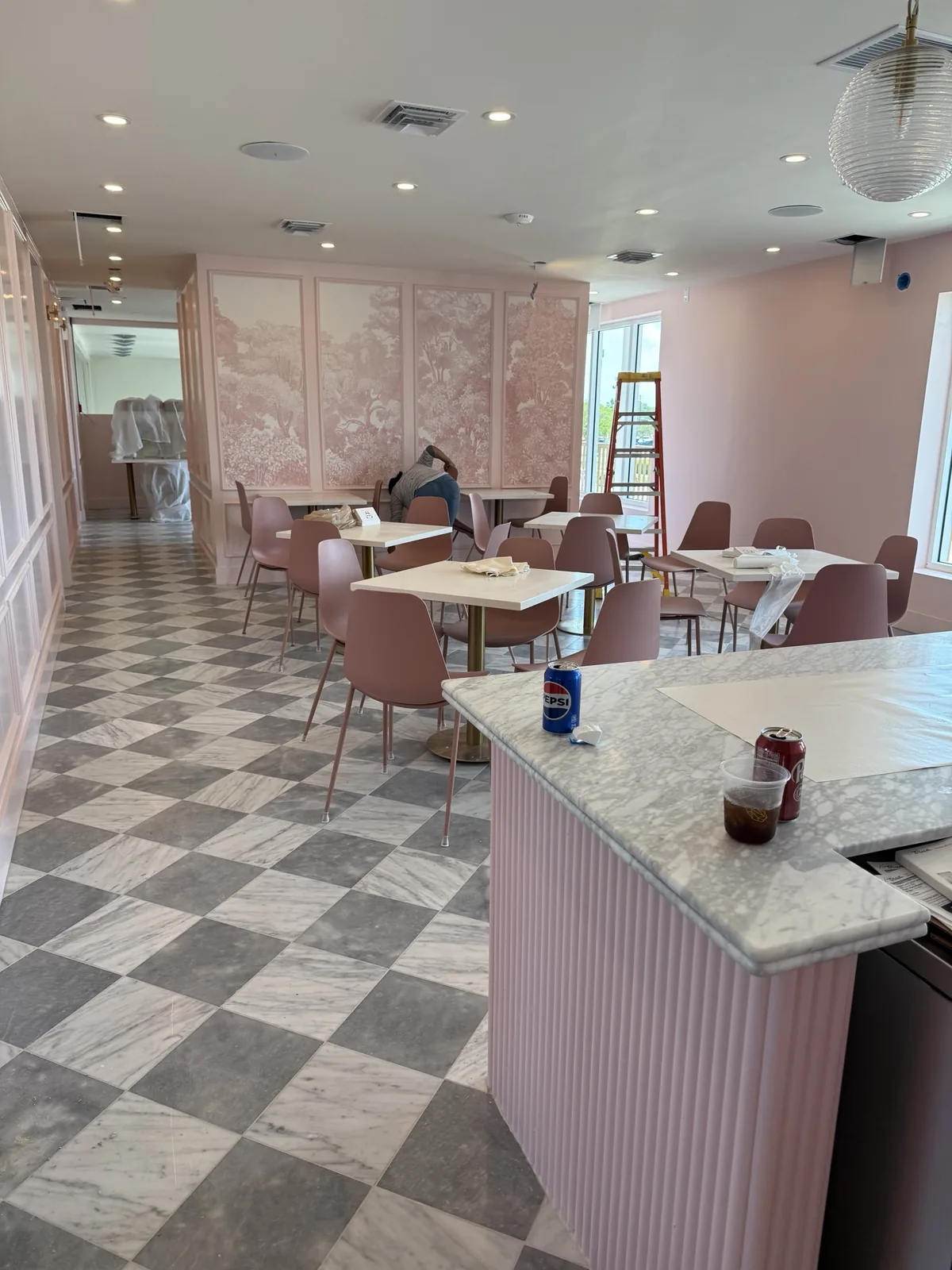 Cafe dining area with scenic wallpaper panels and marble checkerboard floor