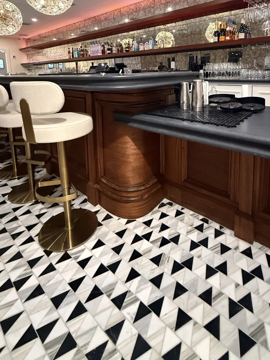 The same curved bar stained and finished, with stools and lit backbar