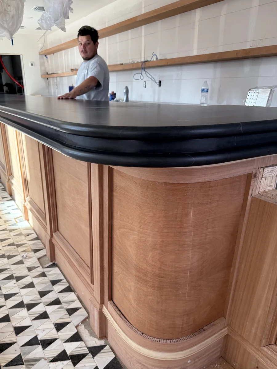 Curved mahogany bar millwork in raw unfinished wood during installation
